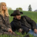 Cole Hauser as Rip Wheeler and Kelly Reilly as Beth Dutton sitting in the grass for a "Yellowstone" stock picture