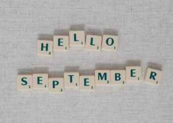 "Scrabble tiles spell 'Hello September' on a textured gray background."