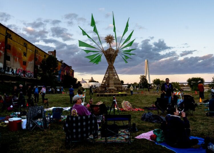 Dozens of festival goers wait for “Our Lady of Artica” to be set ablaze Sunday, Oct. 8, 2023, during the Artica Urban Art Festival along the Mississippi Riverfront in downtown St. Louis.