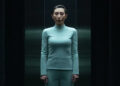 Gemma in light blue wardrobe standing in Testing Floor elevator in Severance Season 2 "Chikhai Bardo".