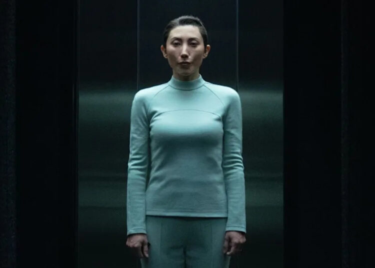 Gemma in light blue wardrobe standing in Testing Floor elevator in Severance Season 2 "Chikhai Bardo".