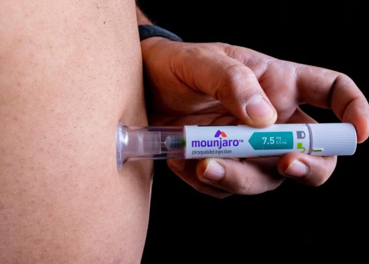 Person injecting Mounjaro pen.