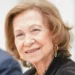Queen Sofía smiling with light brown hair and gold earrings.