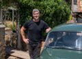 Ant Anstead in black t-shirt posing next to green car