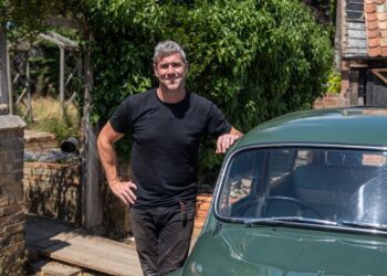 Ant Anstead in black t-shirt posing next to green car