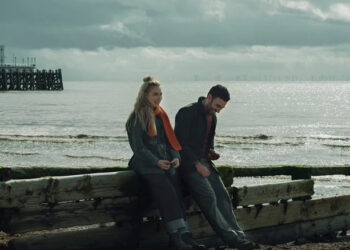 Imogen Poots as Laura and Brett Goldstein as Simon sitting by a pier and laughing in All of You