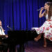 Ariana Grande sings on a piano that Jimmy Fallon in a blonde wig plays.
