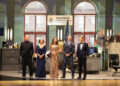 Five people on a stage with a recreation of a set of a New York police office.