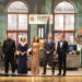Five people on a stage with a recreation of a set of a New York police office.