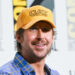 Ryan Gosling in a blue plaid shirt smiles at Comic-Con.
