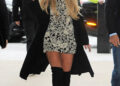 Britney Spears smiles and waves while arriving in a black-and-white floral mini dress, black coat, wide-brim hat, and over-the-knee boots.