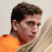 Bryan Kohberger in an orange prison jumpsuit, seated in court and looking to the side during a hearing.