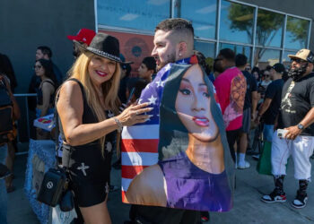 A man and woman stand smiling outside a record store.