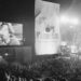 John Cougar Mellencamp performs both on stage and on one of two large screen television screens set up at the University of Illinois Memorial Stadium in Champaign, Ill. on Sept. 22, 1985 during the Farm Aid concert. (AP Photo/Seth Perlman, file)