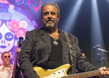 Raul Malo holds a guitar on stage during a concert.