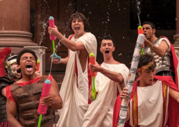 Fraternity brothers with water toys having fun in Amazon Prime's Overcompensating Season 1.