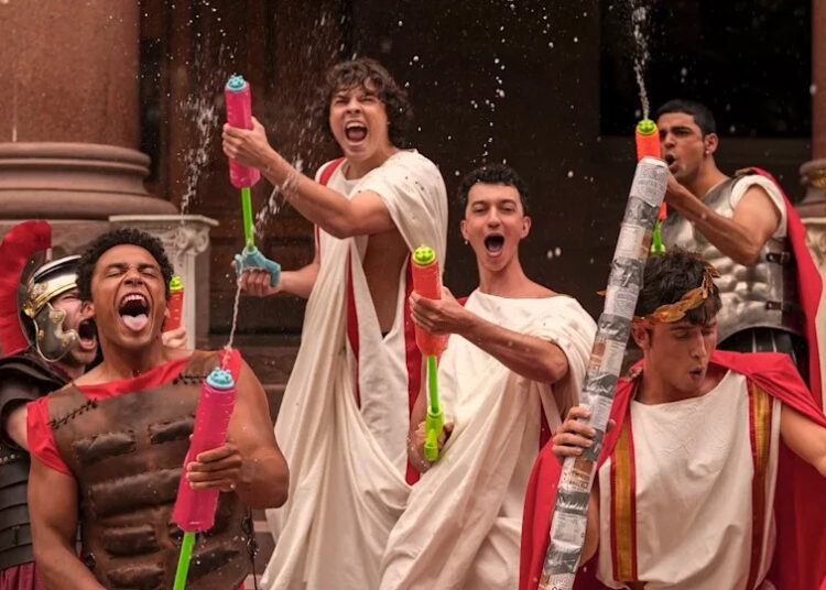 Fraternity brothers with water toys having fun in Amazon Prime's Overcompensating Season 1.