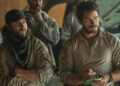 From left to right: Taylor Kitsch standing with his arms crossed and Chris Pratt writing on a notepad in The Terminal List: Dark Wolf. .