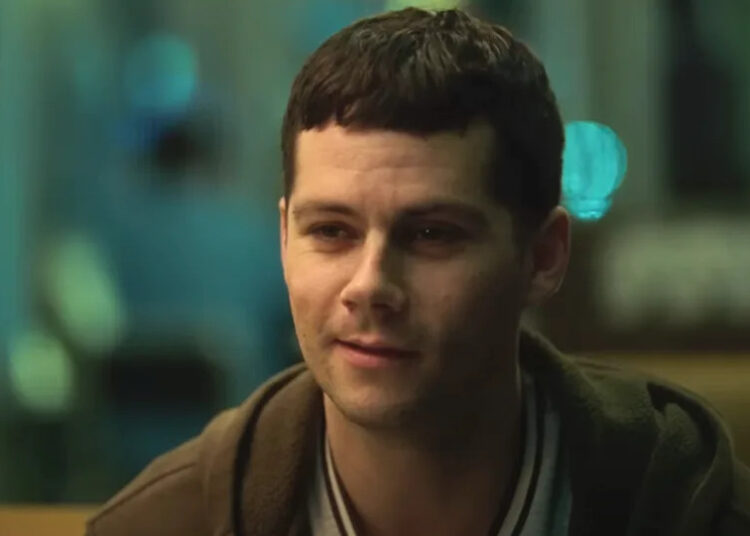 Dylan O'Brien sitting in a diner in Twinless.