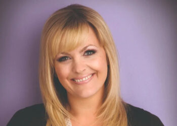 Tanya Branning smiling at the camera with a purple background.