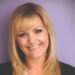 Tanya Branning smiling at the camera with a purple background.