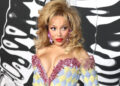 Doja Cat poses in big hair and a colorful dress.