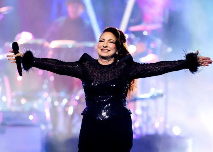 Gloria Estefan raises her arms while performing on stage.