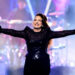 Gloria Estefan raises her arms while performing on stage.