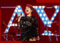 Raye belts onstage in concert.