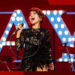 Raye belts onstage in concert.