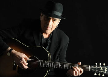Eric Andersen strums the guitar.