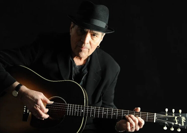 Eric Andersen strums the guitar.