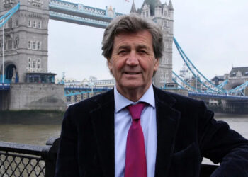 Melvyn Bragg standing by Tower Bridge