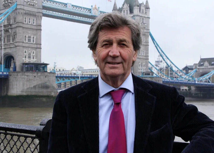Melvyn Bragg standing by Tower Bridge