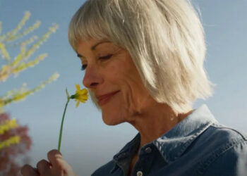 Gus smelling a flower in a scene from The Chicken Sisters.