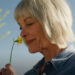 Gus smelling a flower in a scene from The Chicken Sisters.