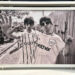 A black-and-white photo of Oasis band members Liam and Noel Gallagher wearing Manchester City football jerseys. Liam holds his hand up, palm facing out, while Noel holds his hand up with his index finger pointing to the sky.
