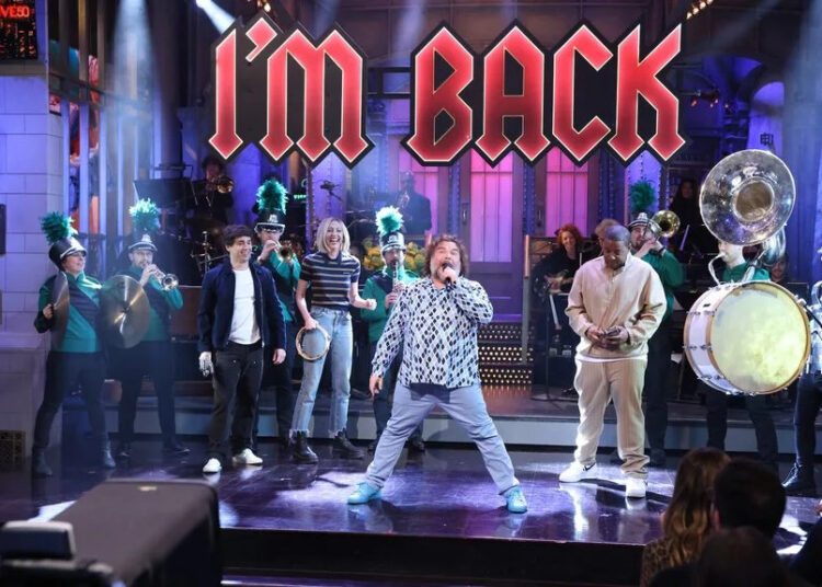 Jack Black surrounded by a marching band in green uniforms with the words "I'm Back" hanging over them.