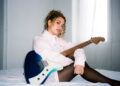 an image of artist Nil&uuml;fer Yanya sitting on a white matress in a bedroom