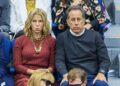 Jerry Seinfeld and his wife Jessica Seinfeld sit in the stands at a sporting event, both with serious expressions.