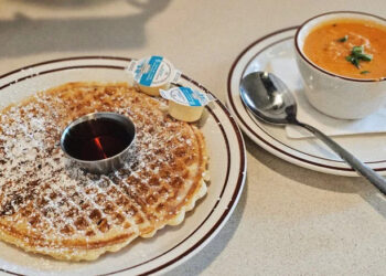 Waffle with powdered sugar on a white plate and soup in a white bowl at Waffle House