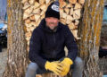 Josh Duhamel smiles as he poses in front of a stack of logs at his Minnesota home.