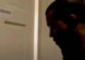 Ye stands near a door labeled