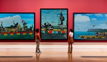 Three paintings hang on a wall in a museum.