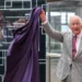 Richard Pohle/Pool via Reuters King Charles pulls a purple cloth from a black glass plaque saying NHS Sandwell and West Birmingham. Welcome to the Midland Metropolitan University Hospital. The plaque is partially obscured by the cloth. He is in a lobby area with glass screens behind him and looking to the left. He is wearing a grey suit and pink tie.