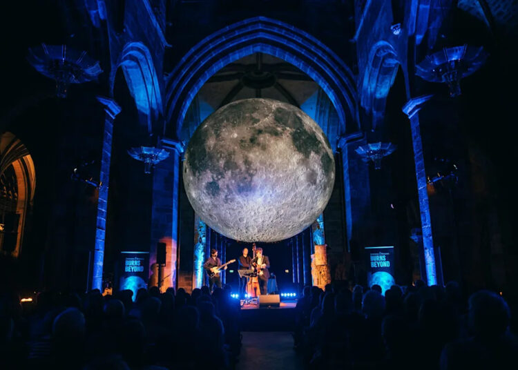 A band performing under the Museum of the Moon at the Burns & Beyond Festival.