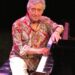 Gil Rosas, wearing a paisley shirt and white pants, sits at the piano. (Rod Lathim photo)