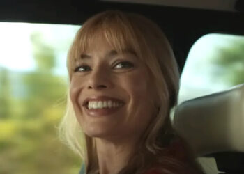 Margot Robbie smiling in passenger seat of car in A Big Bold Beautiful Journey.