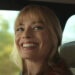 Margot Robbie smiling in passenger seat of car in A Big Bold Beautiful Journey.
