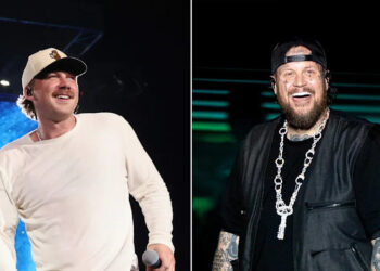 Morgan Wallen wears hat and white shirt on stage next to Jelly Roll in all black.